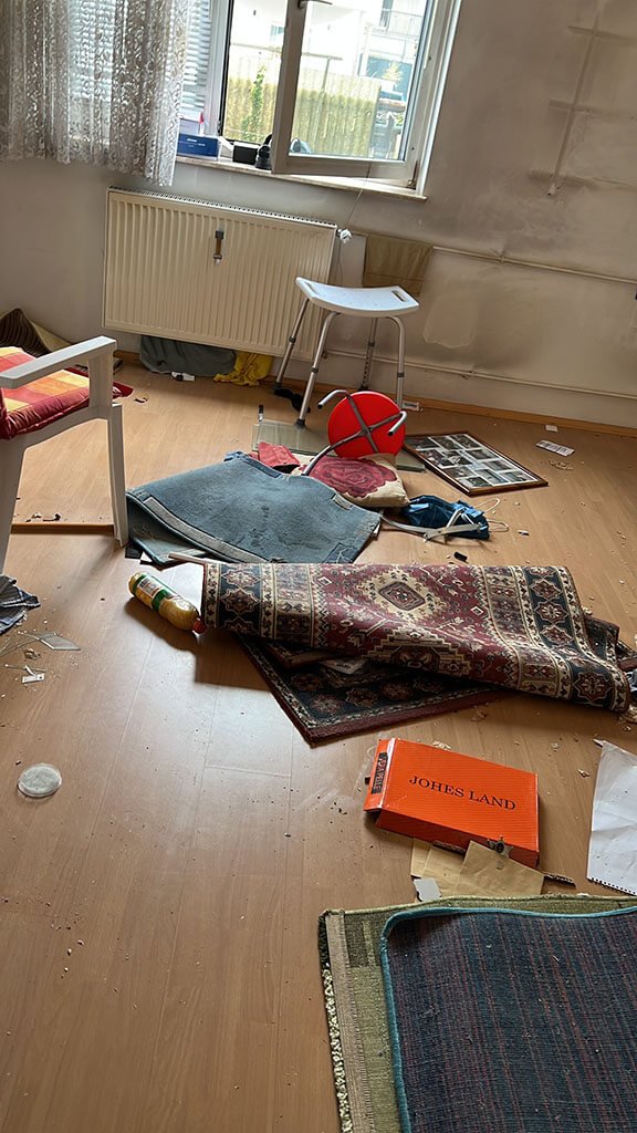 Zimmer mit Teppichen, Stuhl und Gerümpel am Boden