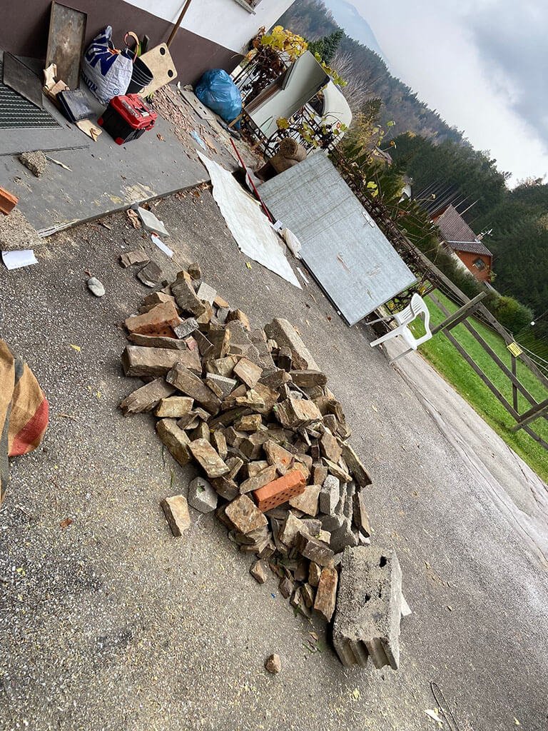 Steinhaufen und Sperrmüll auf einer Einfahrt vor einem Haus
