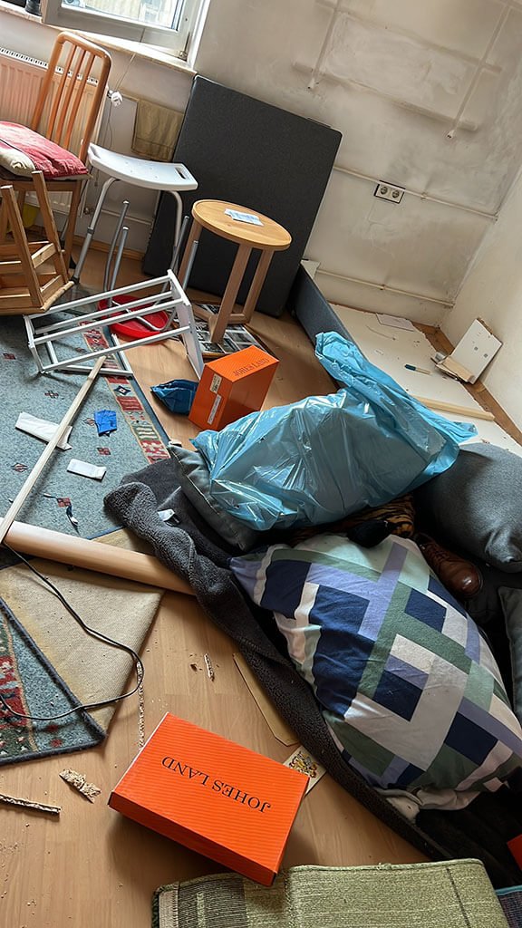 Wohnraum mit Müllsäcken, Kissen, Hocker und Gerümpel am Boden
