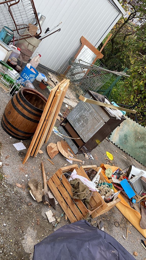 Hof mit Holzfass, Holzlatten, Kisten und alten Gegenständen
