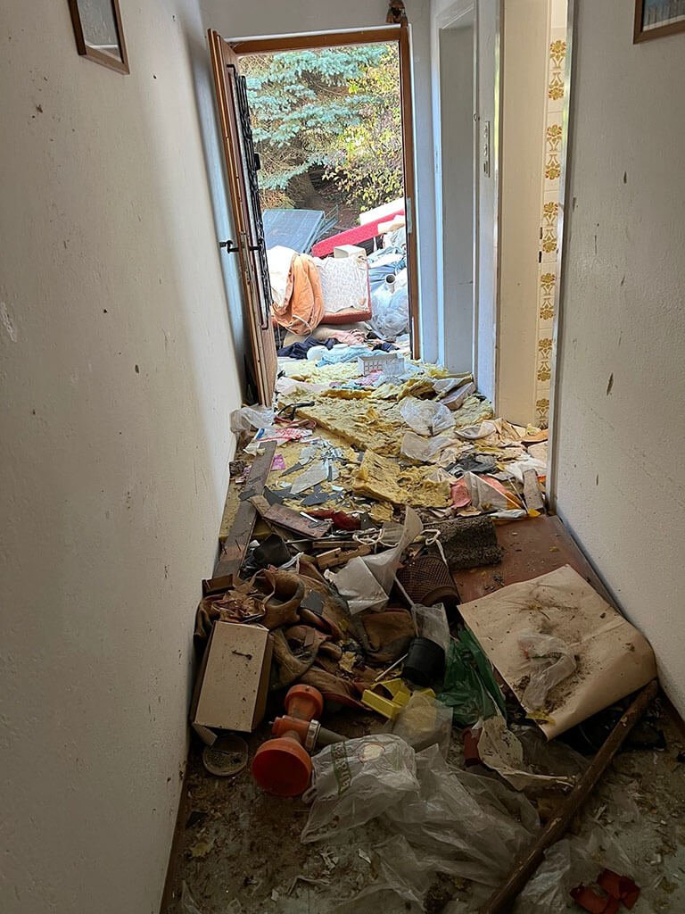 Flur eines Hauses voller Müll und Gerümpel bis zur Eingangstür