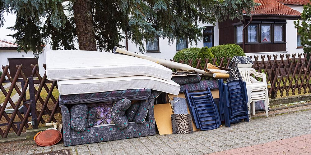 Ausrangierte Möbel und eine Matratze vor einem Haus zur Abholung